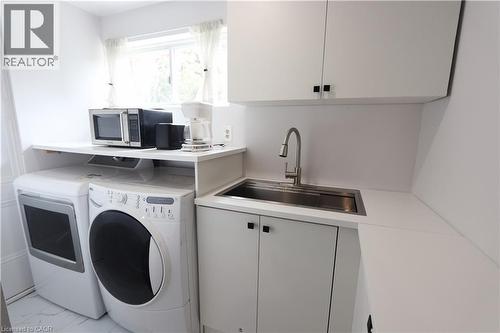 White cabinetry with black hardware, stainless steel sink, and white countertop - 77 Orchard Mill Crescent, Kitchener, ON - Indoor Photo Showing Laundry Room