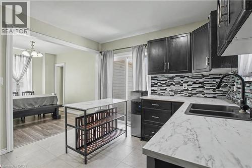 Kitchen featuring dark cabinetry, white countertops, mosaic tile backsplash, and a stainless steel sink with a black faucet - 16 Mercer Road, Cambridge, ON - Indoor Photo Showing Kitchen With Double Sink
