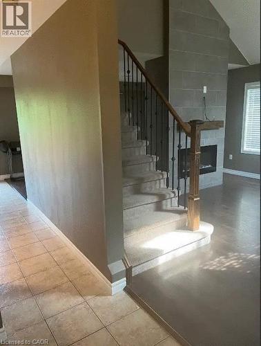 Carpeted staircase with wrought iron balusters and a wood handrail - 4000 Medland Drive, Burlington, ON - Indoor Photo Showing Other Room With Fireplace