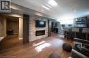 Finished basement featuring wood-finish flooring, recessed lighting, and a stone accent wall with a built-in electric fireplace - 4000 Medland Drive, Burlington, ON  - Indoor Photo Showing Living Room With Fireplace 