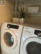 Laundry area featuring a side-by-side washer and dryer, white wire shelving, and neutral wall paint - 