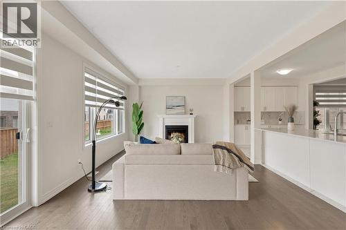 Open-concept living space featuring wood-finish flooring, a fireplace with a mantel, and large windows - 285 Broadacre Drive, Kitchener, ON - Indoor With Fireplace