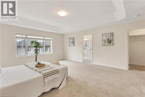 Spacious room with a tray ceiling, large windows, light-toned carpet flooring, and a walk-in closet - 285 Broadacre Drive, Kitchener, ON - Indoor
