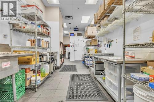 Commercial kitchen space featuring tile flooring, stainless steel workstations, and extensive wire shelving - 589 Fairway Road S, Kitchener, ON 