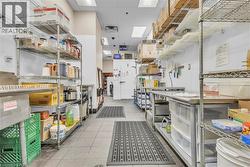 Commercial kitchen space featuring tile flooring, stainless steel workstations, and extensive wire shelving - 