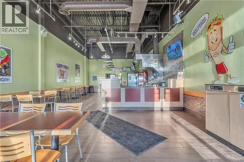 Open-concept commercial space featuring wood-finish flooring, exposed ceiling ductwork, and track lighting - 589 Fairway Road S, Kitchener, ON 