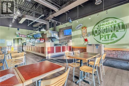 Exposed ceiling ductwork, track lighting fixtures, brick accent wall, service counter with built-in displays, and wood-finish flooring - 589 Fairway Road S, Kitchener, ON 