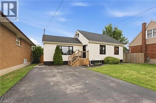 Paved driveway, wood-finish deck with stairs, white siding exterior, dark-frame windows, and a landscaped yard - 481 Upper Gage Avenue, Hamilton, ON - Outdoor
