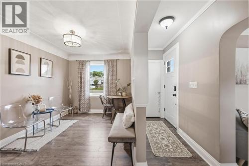 Inviting entryway featuring wood-finish flooring extending into the main living areas, a white entry door, and a decorative overhead light fixture - 481 Upper Gage Avenue, Hamilton, ON - Indoor