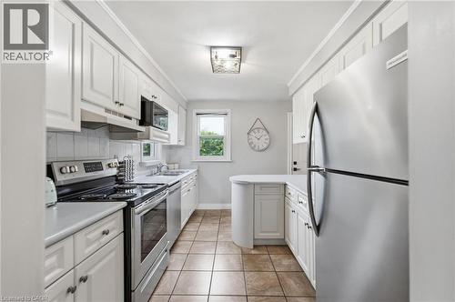 Kitchen featuring white cabinetry, stainless steel appliances, a white tile backsplash, and a curved countertop extension - 481 Upper Gage Avenue, Hamilton, ON - Indoor Photo Showing Kitchen