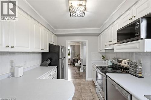 Kitchen featuring white cabinetry, light countertops, stainless steel appliances, and tile flooring - 481 Upper Gage Avenue, Hamilton, ON - Indoor Photo Showing Kitchen