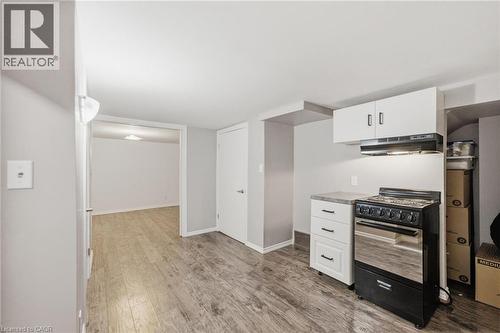 Kitchen area featuring a freestanding black and stainless steel range, range hood, white upper and lower cabinetry with dark hardware, and a light-toned countertop - 481 Upper Gage Avenue, Hamilton, ON - Indoor Photo Showing Other Room