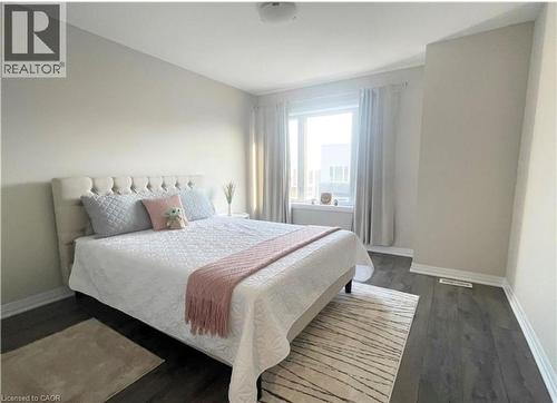 Neutral wall paint, wood-finish flooring, and a window with white trim - 17 Visionary Avenue, Kitchener, ON - Indoor Photo Showing Bedroom