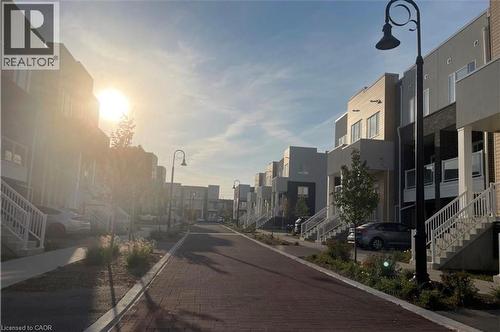 Brick paver pathway with street lighting, flanked by multi-story residential buildings featuring various exterior finishes - 17 Visionary Avenue, Kitchener, ON - Outdoor