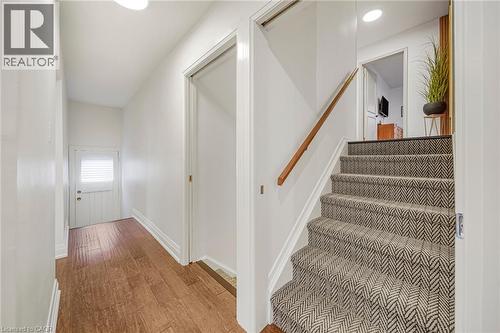 Wood-finish flooring, white paneled door with louvered window, recessed lighting, carpeted stairs with geometric pattern, and a natural wood handrail - 24 Garvey Crescent, Hamilton, ON - Indoor Photo Showing Other Room