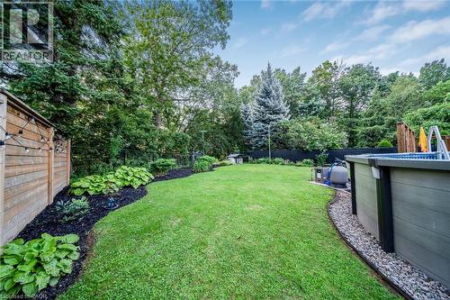 Manicured lawn, mature trees, wood-slat fence, above-ground pool, and landscaped garden beds - 24 Garvey Crescent, Hamilton, ON - Outdoor