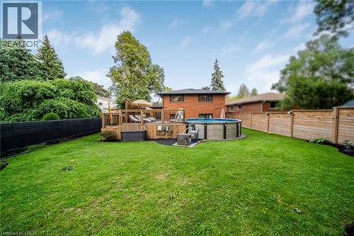 Expansive green lawn with a wood deck, above-ground pool, and wood fencing - 24 Garvey Crescent, Hamilton, ON - Outdoor With Backyard