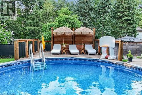 Expansive pool with patterned lining, surrounded by a wood-plank deck with railing, and privacy screen - 24 Garvey Crescent, Hamilton, ON - Outdoor With In Ground Pool With Deck Patio Veranda