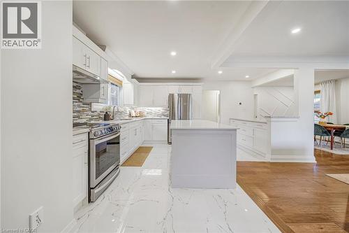 Contemporary kitchen featuring white cabinetry, a central island, stainless steel appliances, and a tiled backsplash - 24 Garvey Crescent, Hamilton, ON - Indoor Photo Showing Kitchen With Upgraded Kitchen