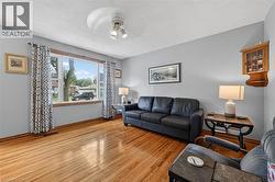 Spacious living area featuring polished wood-finish flooring, a large picture window, light gray wall paint, and a ceiling-mounted track light fixture - 