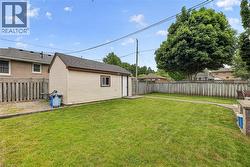 Expansive green lawn with a detached storage shed featuring horizontal siding and a window - 