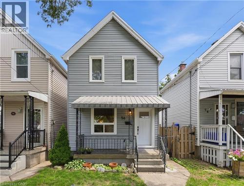 Two-story exterior with horizontal siding, a covered front porch with metal railings, and a white entry door - 56 Harmony Avenue, Hamilton, ON - Outdoor With Deck Patio Veranda