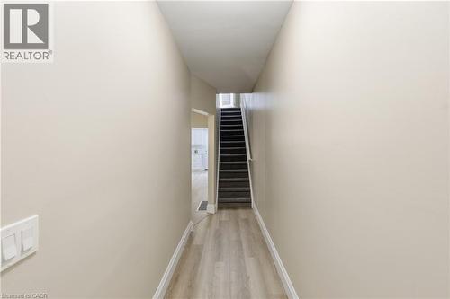Hallway featuring wood-finish flooring, light-toned walls, and a carpeted staircase - 56 Harmony Avenue, Hamilton, ON - Indoor Photo Showing Other Room