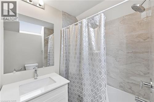 White vanity with an integrated rectangular sink, chrome faucet, and expansive wall mirror - 56 Harmony Avenue, Hamilton, ON - Indoor Photo Showing Bathroom