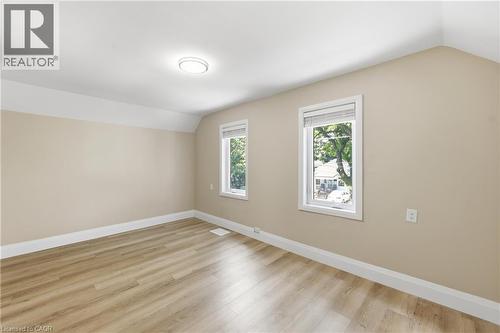 Neutral wall tones, wood-finish flooring, two windows with white blinds, and a flush-mount ceiling light - 56 Harmony Avenue, Hamilton, ON - Indoor Photo Showing Other Room