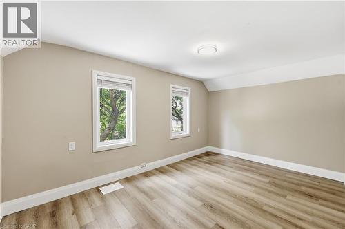Wood-finish flooring with white trim, neutral wall color, two windows, and a flush-mount ceiling light - 56 Harmony Avenue, Hamilton, ON - Indoor Photo Showing Other Room
