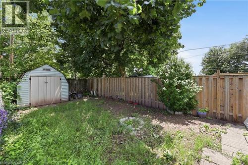 Expansive outdoor space featuring a storage shed, wood privacy fencing, and mature trees - 56 Harmony Avenue, Hamilton, ON - Outdoor