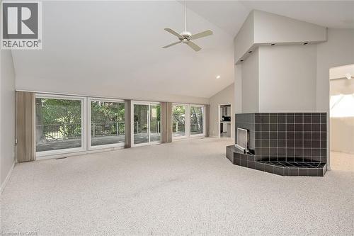 Vaulted ceiling, ceiling fan, expansive sliding glass doors, black tiled fireplace, and light-colored carpeting - 4189 Inglewood Drive, Burlington, ON - Indoor Photo Showing Other Room