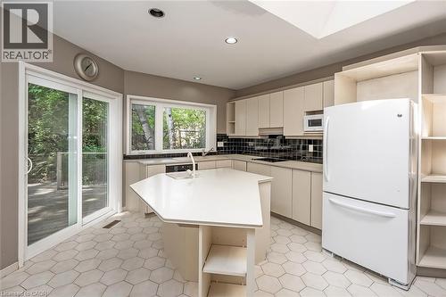 Kitchen featuring hexagonal floor tiling, sliding glass door, white cabinetry, an island with an integrated sink, and recessed lighting - 4189 Inglewood Drive, Burlington, ON - Indoor Photo Showing Kitchen
