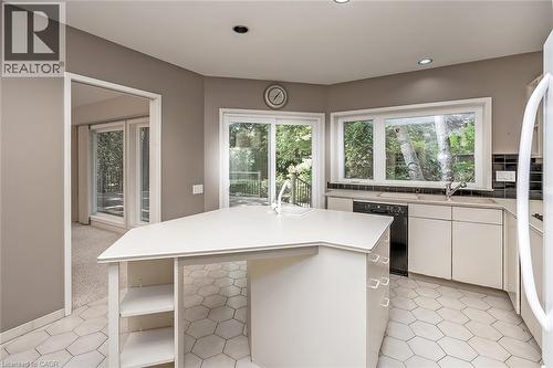 Kitchen featuring a center island, white cabinetry, integrated sink, and an appliance suite - 4189 Inglewood Drive, Burlington, ON - Indoor Photo Showing Kitchen With Double Sink