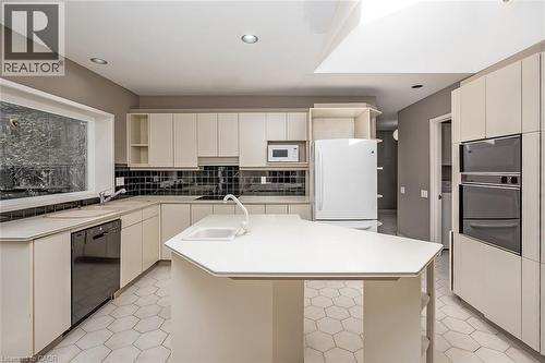 Kitchen featuring hexagonal tile flooring, light-toned cabinetry, a skylight, a large window, and integrated double ovens - 4189 Inglewood Drive, Burlington, ON - Indoor Photo Showing Kitchen With Double Sink
