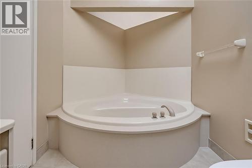 Corner soaking tub with deck-mounted fixtures, built-in shelving, and neutral wall tones - 4189 Inglewood Drive, Burlington, ON - Indoor Photo Showing Bathroom