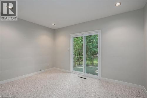 Recessed ceiling lighting, light gray wall paint, patterned carpeting, and white sliding glass doors opening to an exterior deck - 4189 Inglewood Drive, Burlington, ON - Indoor Photo Showing Other Room
