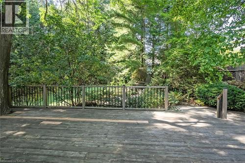 Expansive wood deck with a dark wood railing, surrounded by mature trees and lush landscaping - 4189 Inglewood Drive, Burlington, ON - Outdoor