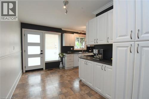 Kitchen featuring extensive white cabinetry, dark countertops, and a stainless steel sink - 374 Brigadoon Drive, Hamilton, ON - Indoor Photo Showing Kitchen