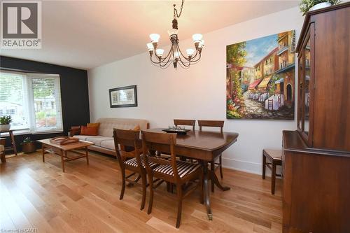Hardwood flooring, bay window with blinds, modern chandelier, dark accent wall, and built-in wood cabinetry - 374 Brigadoon Drive, Hamilton, ON - Indoor Photo Showing Dining Room