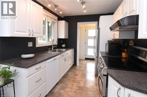 White shaker-style cabinetry, dark speckled countertops, stainless steel sink with gooseneck faucet, integrated dishwasher, and track lighting - 374 Brigadoon Drive, Hamilton, ON - Indoor Photo Showing Kitchen