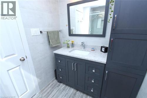White paneled door opening to a bathroom featuring a vanity with a white rectangular sink, light-colored countertop, and dark cabinetry - 374 Brigadoon Drive, Hamilton, ON - Indoor Photo Showing Bathroom