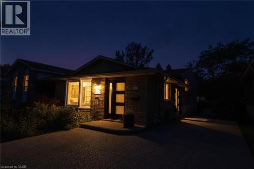 Brick facade with a contemporary entry door, exterior lighting, and a paved driveway - 374 Brigadoon Drive, Hamilton, ON - Outdoor