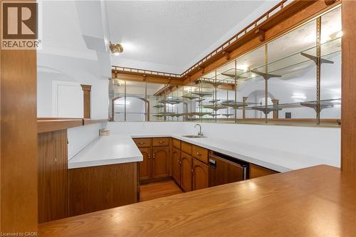 Custom wet bar featuring wood-finish cabinetry, solid surface countertops, and an undermount sink - 35 Glen Park Court, Hamilton, ON - Indoor Photo Showing Kitchen