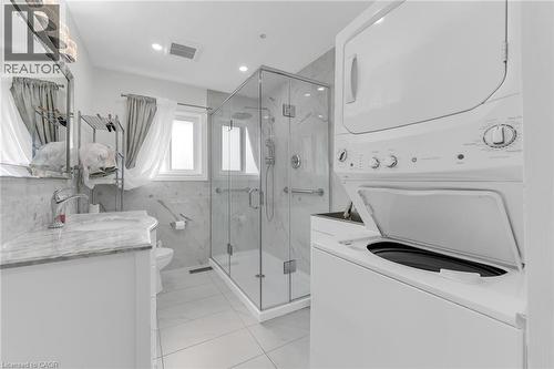 Contemporary bathroom featuring a glass-enclosed shower, built-in vanity with a stone countertop, and a stacked washer and dryer - 35 Glen Park Court, Hamilton, ON - Indoor Photo Showing Laundry Room