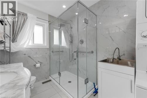 Glass-enclosed shower with a rainfall showerhead, white marble-look wall tiling, and a window for natural light - 35 Glen Park Court, Hamilton, ON - Indoor Photo Showing Bathroom