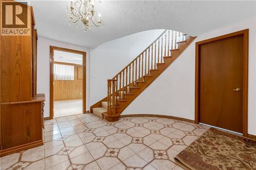 Entryway featuring patterned tile flooring, a curved staircase with wood banister, and a chandelier - 35 Glen Park Court, Hamilton, ON - Indoor Photo Showing Other Room