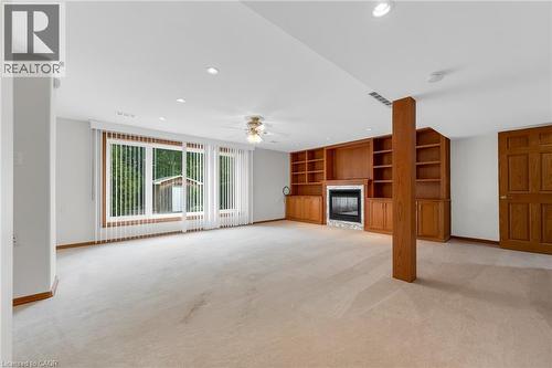 Spacious room with recessed lighting, integrated wood cabinetry, a fireplace with a stone surround, and large windows - 35 Glen Park Court, Hamilton, ON - Indoor With Fireplace