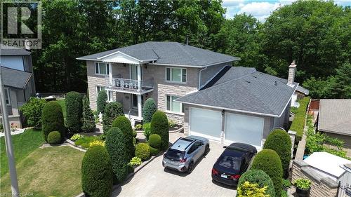 Stone facade with a prominent second-story balcony, mature topiary landscaping, and a two-car garage with white doors - 35 Glen Park Court, Hamilton, ON - Outdoor