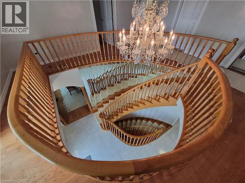 Spiral staircase with wood banister, crystal chandelier, wood-finish flooring, and light-toned tile - 35 Glen Park Court, Hamilton, ON - Indoor Photo Showing Other Room